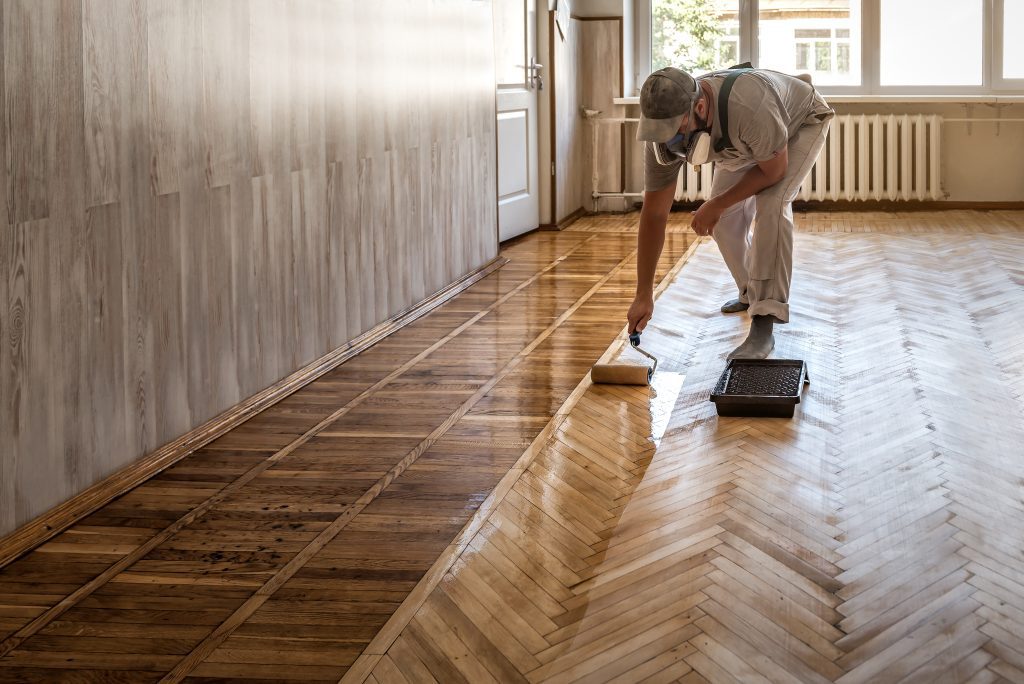 worker lacquering parquet floors